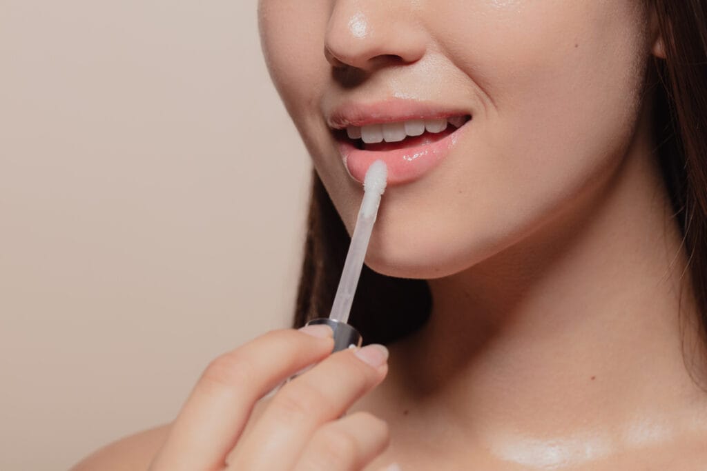 Woman applying lip gloss for fuller lips